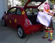 Silly Jilly the Clown loads up her red Fiat 500 with her magic suitcase. 